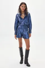 Camisa azul metalizada de lino, con mangas largas y ruedo curvo más largo atrás.