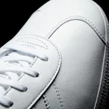 Championes Adidas Gazelle blancos de cuero con las tres tiras características de la marca en los laterales y el nombre del modelo en dorado.