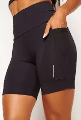 Calza biker deportiva negra, de tiro alto, con bolsillos laterales y bolsillo interno en la cintura. Presenta detalles reflectivos.