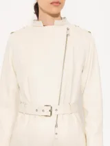 Tapado color crema confeccionado en cuero ovino, con largo hasta arriba de la rodilla. Presenta costadillos, espalda y bajo mangas en complemento al tono que aportan textura. Incluye cinturón en cuero base, bolsillos ojal verticales en el frente y canesú matelaseado. El acceso es mediante cierre metálico al frente.