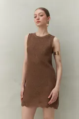 Vestido de tejido con trama abierta y caída liviana, confeccionado en un hilado con acabado metalizado. Silueta recta y sin mangas.