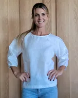 Blusa blanca de lino con mangas 3/4 abullonadas y detalle de cinta en los hombros.