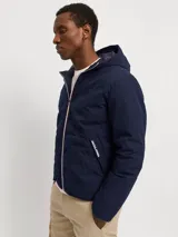 Campera híbrida Jack & Jones color azul marino, ligera y resistente al agua, con capucha, mangas largas con puños elásticos, cierre con cremallera y bolsillos frontales con cierre. Relleno de fibra sintética tipo plumón.