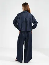 Camisa azul marino de lino italiano con hilo metalizado, cuello clásico, silueta fluida y botón en forma de flor en el cuello.