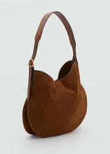 Bolso tipo hobo de gamuza color marrón con patrón de logo estampado. Tiene asa de hombro ajustable con hebilla dorada y cierre magnético.