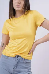 Remera ajustada de manga corta, color amarillo vibrante, con cuello redondo. Presenta un pequeño detalle de etiqueta negra en la manga derecha.