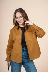 Camisa marrón de corte clásico, con tejido suave y textura cálida. Tiene un bolsillo decorativo discreto y botones al tono.