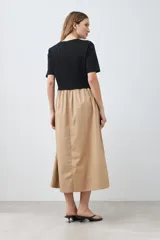 Vestido midi de corte recto, con top negro de mangas cortas y falda color beige.
