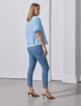 Blusa celeste de gasa marca Zac & Rachel, con cuello redondo, frunces en el frente, mangas 3/4 con puño, abertura central en la espalda y botón.