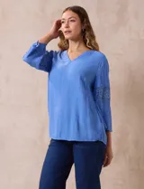 Blusa celeste de gasa bambula con cuello a la base y escote en V. Manga ¾ amplia, con aplique de crochet en los puños.