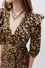 Vestido midi con estampado animal print de leopardo, escote en V cruzado, mangas 3/4 con volados en los hombros, cinturón negro con aplique de flor y volados en el ruedo.