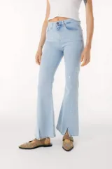 Pantalón de jean azul de corte acampanado con aberturas en el ruedo.