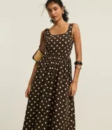 Vestido midi evasé de tricolina color marrón con lunares blancos, breteles anchos y escote cuadrado. Presenta lastex en la espalda y recorte fruncido en la cintura.