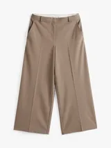 Pantalón de vestir color beige, de corte tobillero y pierna ancha. Confeccionado en tejido antiarrugas de mezcla de poliéster, viscosa y elastano. Presenta cierre de cremallera con enganche oculto, raya marcada en la parte delantera y trasera, y dos bolsillos traseros de ojal.