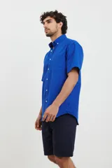 Camisa de manga corta azul con pequeños lunares blancos, cuello button-down y bolsillo en el pecho.