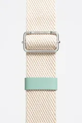 Bolso tipo bucket de nylon color beige, con estructura blanda, cierre de cordón y asa de tejido regulable. Presenta logo metálico de Bimba y Lola en el frente.