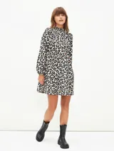 Vestido corto negro con cuello alto, mangas largas abullonadas y falda escalonada.