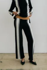 Pantalón de punto color crudo con rayas verticales negras a los costados.