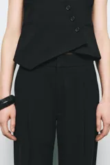 Pantalón negro de tiro alto con bolsillos delanteros, pinzas delanteras y cierre frontal con cremallera y ganchos metálicos.