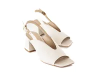 Sandalias de tacón bloque color blanco hueso, con punta cuadrada y talón descubierto. Presentan una tira delgada ajustable con hebilla dorada en el tobillo.