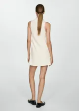 Vestido corto evasé color crudo, de tejido de punto fino, sin mangas y con cuello perkins.