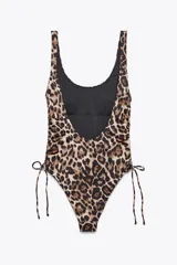 Bañador enterizo con estampado animal print, copas extraíbles, escote redondo y tirantes. Detalle de frunces ajustables con lazadas en los laterales y forro interior.