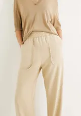 Pantalón negro de tiro alto con cintura elástica fruncida y bolsillos tipo parche redondeados en la parte delantera. El corte es recto y el bajo está doblado.