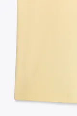 Camiseta corta de algodón color amarillo pastel, de corte recto, cuello redondo y manga corta. Detalle de costura marcada en la espalda.