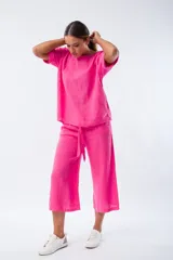 Conjunto fucsia de lino, compuesto por una blusa de mangas cortas y un pantalón capri con lazo en la cintura.