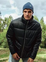 Campera puffer negra de poliéster con cuello alto, cierre frontal con cremallera, bolsillos laterales con solapa y puños elásticos.