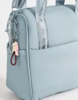 Cartera shopper negra de tela deportiva con doble asa corta estampada, correa regulable y desmontable, cierre superior con puller de goma y charm lateral.