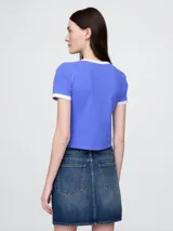 Remera corta azul con cuello redondo y mangas cortas con ribete blanco. Estampado frontal con la leyenda "New York" y el logo de Gap.