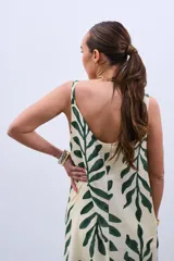 Vestido largo color crudo con estampado de hojas verdes, de corte amplio y breteles finos.