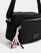 Bandolera negra de tela deportiva con bolsillo frontal con cierre, correa regulable, cierre superior y tag de goma.
