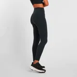 Calza larga de training New Balance modelo Harmony High Rise, color negro, con cintura alta y logo reflectivo en la pierna.