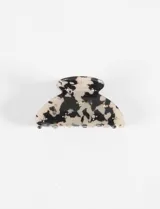 Broche para el pelo tipo pinza, color crema con manchas negras y pequeños strass plateados.