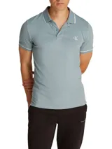 Chomba de piqué celeste con cuello polo, mangas cortas y corte slim. Presenta tapeta de dos botones, logo CK bordado en el pecho y ribetes blancos en cuello y mangas.