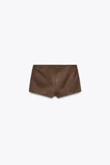 Shorts de tiro alto color marrón, confeccionados en tejido efecto ante con aplicación de tachas doradas. Cierre lateral con cremallera oculta.