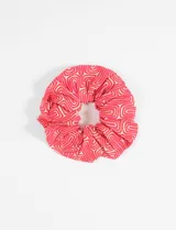 Scrunchie de viscosa con estampado de líneas curvas en tonos rojo y blanco.
