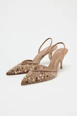Zapato destalonado color beige con puntera fina, confeccionado en mesh con abalorios y tira trasera elástica. Tacón fino de 8 cm.
