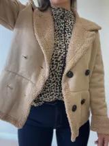 Chaqueta marrón con forro tipo corderito, doble botonadura y cuello con solapas.