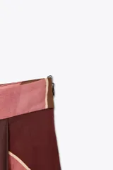 Falda midi de tiro alto confeccionada en hilatura de algodón con estampado geométrico multicolor. Detalle de pliegues en cintura y bajo evasé. Cierre con cremallera oculta en costura.