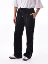 Pantalón de jogging negro con cintura elástica ajustable con cordón, bolsillos laterales y detalle de encaje en los laterales.
