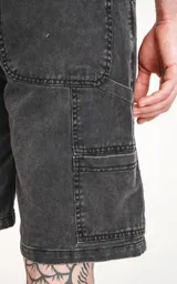 Bermuda de denim negro con calce oversize, estilo carpintero y bolsillo lateral.