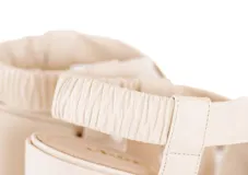 Sandalia de cuero color blanco hueso, con tiras cruzadas acolchadas, talón elástico fruncido, taco ancho de 6 cm y punta cuadrada.