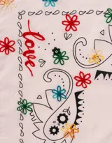 Pañuelo de tela color rosa claro con estampado de flores y letras en negro, rojo y verde.