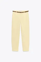 Pantalón chino color amarillo claro, de tiro medio, con bolsillos frontales y traseros. Incluye cinturón trenzado marrón.