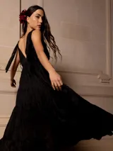 Vestido largo negro con escote en V, breteles finos con lazo y bordados florales a tono. Corte imperio y falda amplia con volados. 