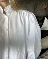 Camisa blanca de mangas largas abullonadas con puños fruncidos y cuello alto con volados.