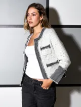Chaqueta Nanette de tejido tweed color blanco con detalles en denim gris. Tiene cuello a la base, abertura central, bolsillos delanteros, puños con aplique de botones perlados, terminación desflecada y forro interno.